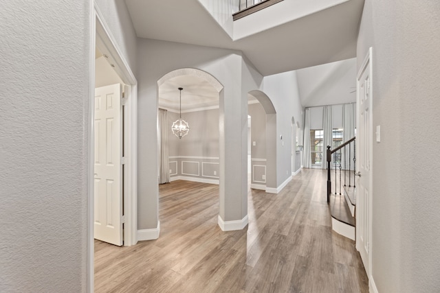 1317 Ocotillo, Fort Worth, TX 76177 - foyer featuring arched walkways, light wood-type flooring, a textured wall, stairs, and a chandelier
