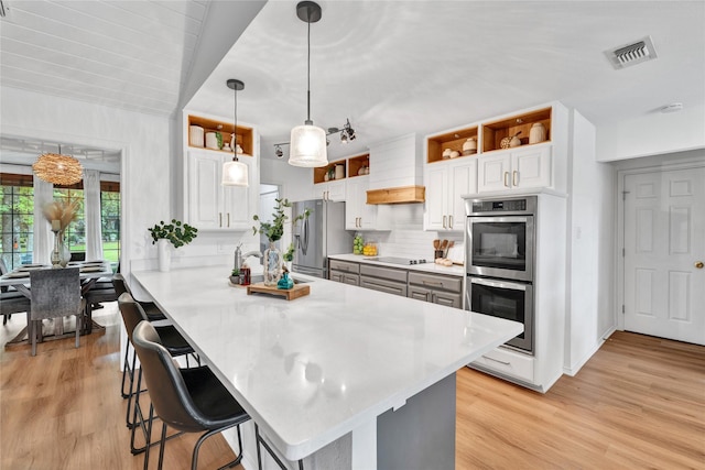 413 Timberlake Dr, Azle, TX 76020 - kitchen with stainless steel appliances, open shelves, a breakfast bar area, light wood-style floors, and white cabinets