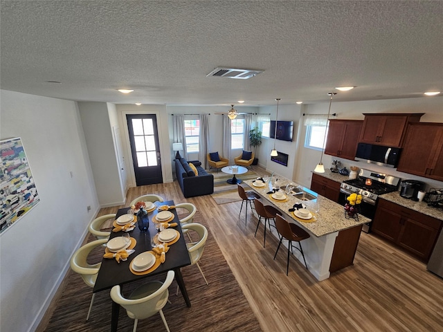 1836 Summer Aura, Mesquite, TX 75181 - kitchen with black microwave, stainless steel range with gas cooktop, baseboards, wood finished floors, and a breakfast bar area