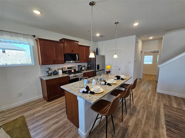 1836 Summer Aura, Mesquite, TX 75181 - kitchen with stainless steel appliances, a kitchen breakfast bar, light wood-style flooring, baseboards, and an island with sink