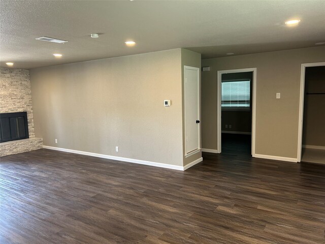 3837 Burning Tree Ln, Garland, TX 75042 - unfurnished living room with dark wood-style floors, baseboards, recessed lighting, a stone fireplace, and a textured ceiling