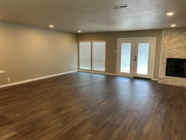 3837 Burning Tree Ln, Garland, TX 75042 - unfurnished living room with baseboards, dark wood-style floors, a fireplace, recessed lighting, and a textured ceiling