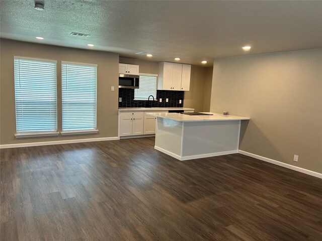 3837 Burning Tree Ln, Garland, TX 75042 - kitchen with stainless steel microwave, dark wood-type flooring, white cabinets, baseboards, and recessed lighting