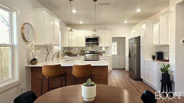 1742 S 5th St, Abilene, TX 79602 - kitchen with appliances with stainless steel finishes, a peninsula, decorative backsplash, wood finished floors, and light countertops
