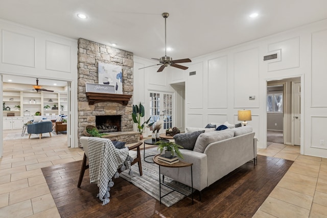 1094 Edith Cir, Richardson, TX 75080 - living room featuring a ceiling fan, a decorative wall, a stone fireplace, recessed lighting, and wood finished floors