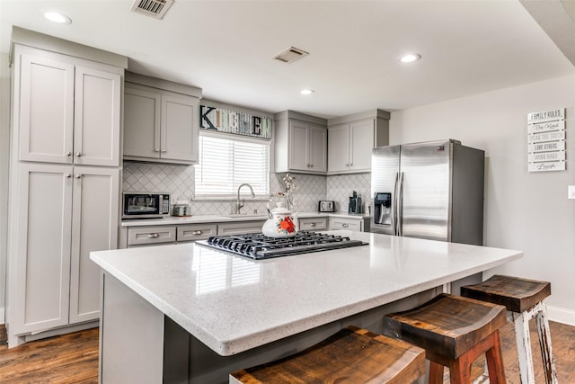 409 N Arizona, Celina, TX 75009 - kitchen with appliances with stainless steel finishes, gray cabinetry, dark wood-style floors, a sink, and a breakfast bar area