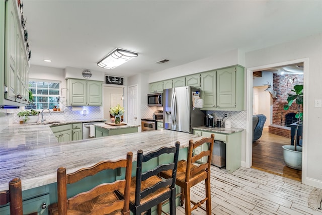 7227 N Stone Meadow Cir, Rowlett, TX 75088 - kitchen with green cabinetry, stainless steel appliances, a sink, light countertops, and tasteful backsplash