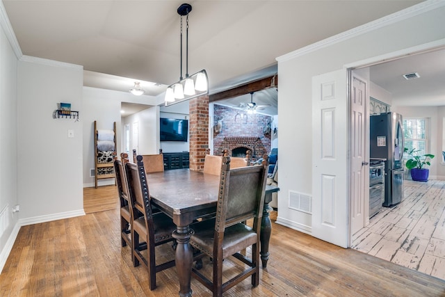 7227 N Stone Meadow Cir, Rowlett, TX 75088 - dining area with light wood-style flooring, ceiling fan, baseboards, a brick fireplace, and ornamental molding