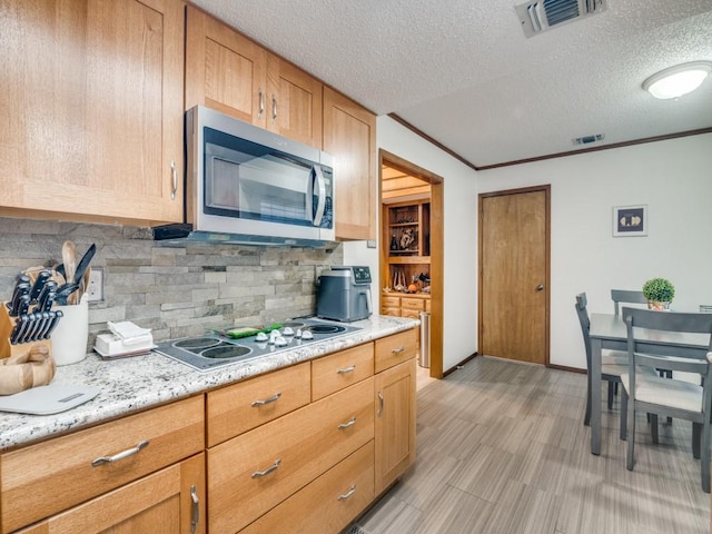 3606 Andrea Ln, Rowlett, TX 75088 - kitchen featuring stainless steel microwave, electric stovetop, decorative backsplash, a textured ceiling, and light wood-type flooring