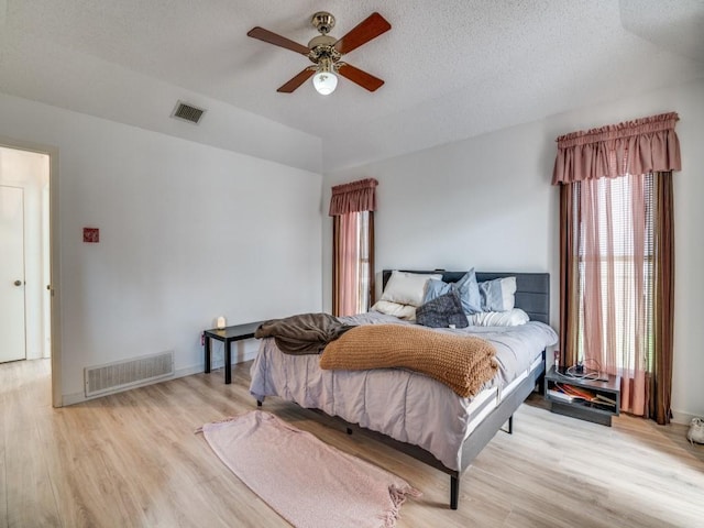 3606 Andrea Ln, Rowlett, TX 75088 - bedroom featuring multiple windows, light wood finished floors, a ceiling fan, vaulted ceiling, and a textured ceiling