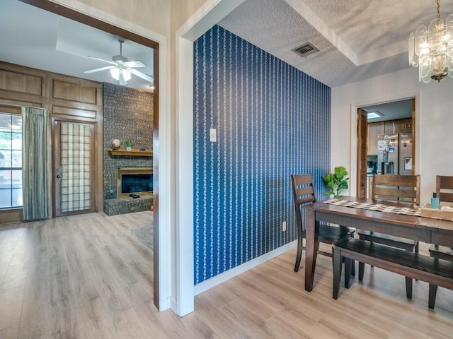 3606 Andrea Ln, Rowlett, TX 75088 - dining room featuring a chandelier, light wood-style floors, a ceiling fan, a fireplace, and a textured ceiling