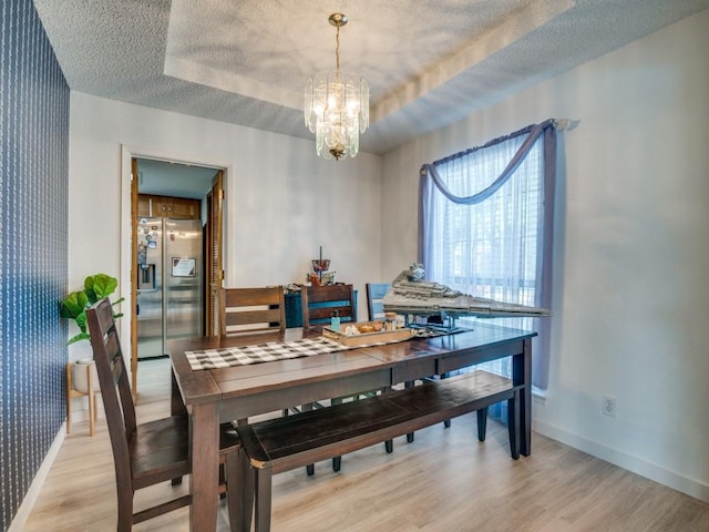 3606 Andrea Ln, Rowlett, TX 75088 - dining area featuring a chandelier, a textured ceiling, light wood-style flooring, baseboards, and a tray ceiling