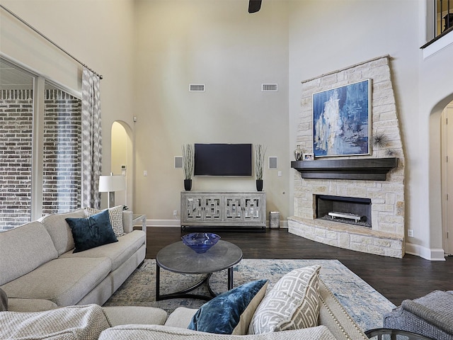 3644 Benchmark Ln, Frisco, TX 75034 - living room featuring arched walkways, a towering ceiling, wood finished floors, and a stone fireplace
