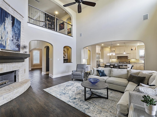 3644 Benchmark Ln, Frisco, TX 75034 - living area featuring a ceiling fan, a high ceiling, dark wood-type flooring, a fireplace, and arched walkways