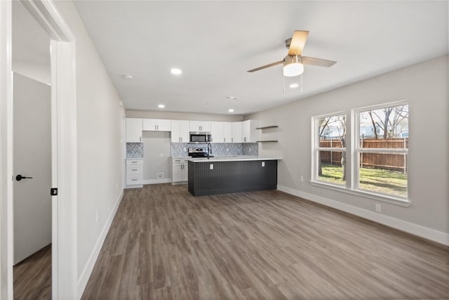 4203 Humphrey Dr, Dallas, TX 75216 - kitchen with appliances with stainless steel finishes, white cabinets, decorative backsplash, a peninsula, and light countertops