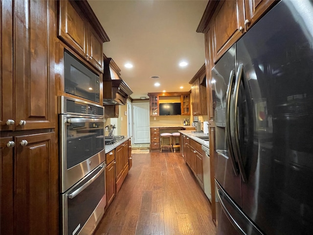 1635 W Pentagon Pkwy, Dallas, TX 75224 - kitchen featuring appliances with stainless steel finishes, dark wood finished floors, wall chimney exhaust hood, light countertops, and glass insert cabinets