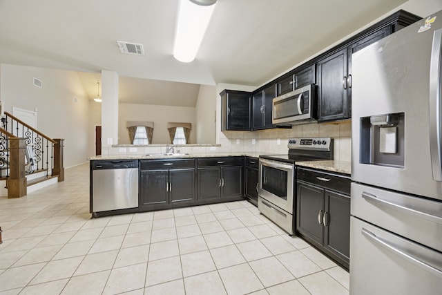 1035 Sadie St, Forney, TX 75126 - kitchen featuring stainless steel appliances, a sink, dark cabinets, tasteful backsplash, and light tile patterned floors