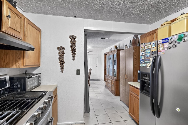 2226 Varsity Dr, Grand Prairie, TX 75051 - kitchen with stainless steel appliances, a textured ceiling, light tile patterned floors, light countertops, and brown cabinets