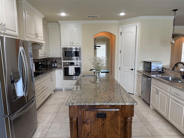 321 Bear Country Dr, Aledo, TX 76008 - kitchen featuring appliances with stainless steel finishes, arched walkways, a sink, a center island, and light tile patterned flooring
