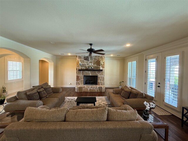 321 Bear Country Dr, Aledo, TX 76008 - living room with arched walkways, ceiling fan, ornamental molding, dark wood-style floors, and a stone fireplace