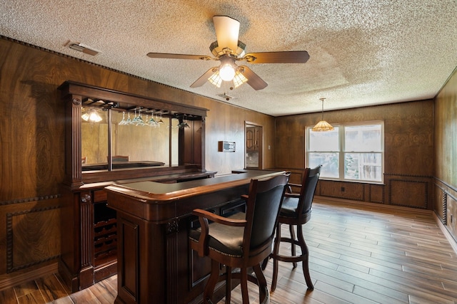 110 S Capri Dr, Duncanville, TX 75116 - indoor dry bar with a textured ceiling, wooden walls, wood finished floors, and ceiling fan