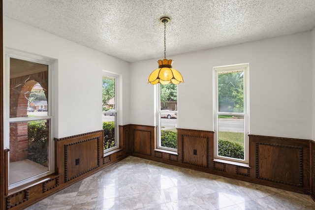 110 S Capri Dr, Duncanville, TX 75116 - unfurnished dining area with wainscoting, plenty of natural light, a textured ceiling, and wooden walls