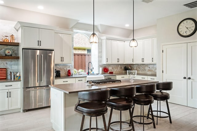 6717 Alcove Ln, Plano, TX 75024 - kitchen with appliances with stainless steel finishes, tasteful backsplash, a breakfast bar area, dark countertops, and hanging light fixtures