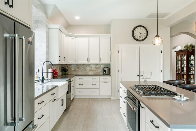 6717 Alcove Ln, Plano, TX 75024 - kitchen with stainless steel appliances, arched walkways, a kitchen island, backsplash, and white cabinetry