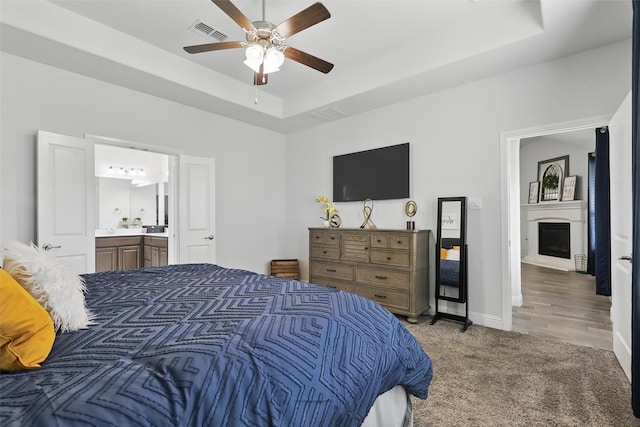 14825 Complacent Way, Aledo, TX 76008 - bedroom featuring a fireplace, a raised ceiling, carpet flooring, ensuite bathroom, and a ceiling fan