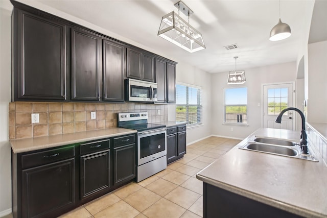 6321 Stone Lake Dr, Fort Worth, TX 76179 - kitchen featuring appliances with stainless steel finishes, a sink, light tile patterned flooring, backsplash, and decorative light fixtures