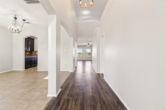 6321 Stone Lake Dr, Fort Worth, TX 76179 - hallway with arched walkways, a chandelier, baseboards, and light wood-style floors