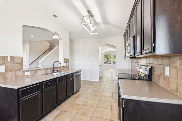 6321 Stone Lake Dr, Fort Worth, TX 76179 - kitchen featuring arched walkways, appliances with stainless steel finishes, a sink, decorative backsplash, and light tile patterned floors