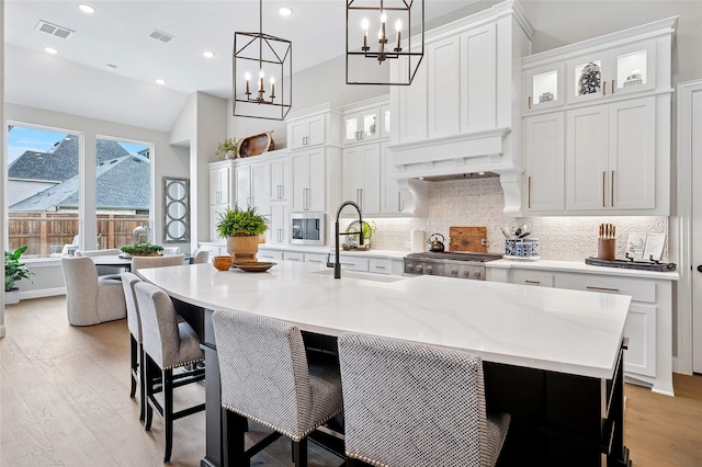 3228 Zenyatta Ct, Celina, TX 75009 - kitchen featuring stainless steel microwave, light wood-style floors, a chandelier, a sink, and decorative backsplash