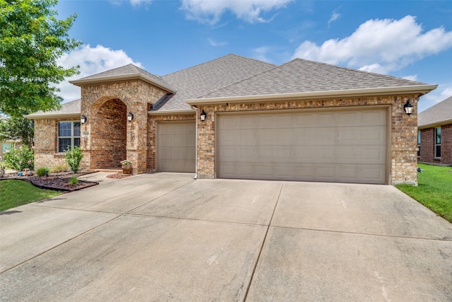 3118 Oak Crest Dr, Royse City, TX 75189 - french country style house with concrete driveway, a shingled roof, an attached garage, and brick siding