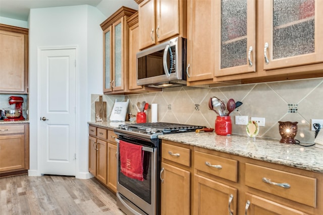 3118 Oak Crest Dr, Royse City, TX 75189 - kitchen with appliances with stainless steel finishes, light wood-type flooring, light stone countertops, and backsplash