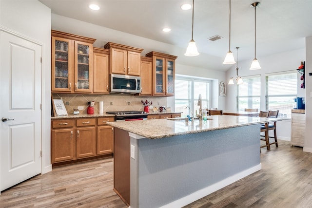 3118 Oak Crest Dr, Royse City, TX 75189 - kitchen with appliances with stainless steel finishes, brown cabinetry, light stone counters, light wood-type flooring, and backsplash