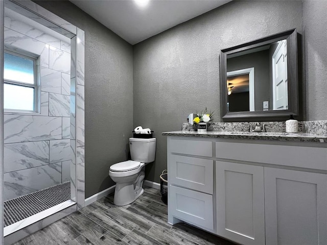 1432 Hurstview Dr, Hurst, TX 76053 - bathroom featuring tiled shower, vanity, toilet, wood finished floors, and a textured wall