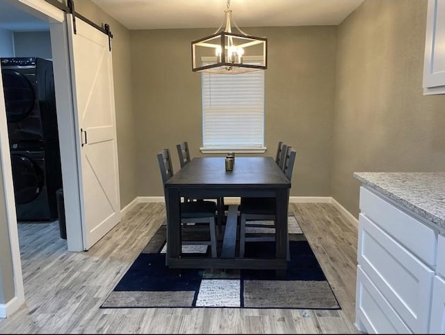1432 Hurstview Dr, Hurst, TX 76053 - dining space with estacked washer and dryer, a barn door, light wood-type flooring, and a chandelier
