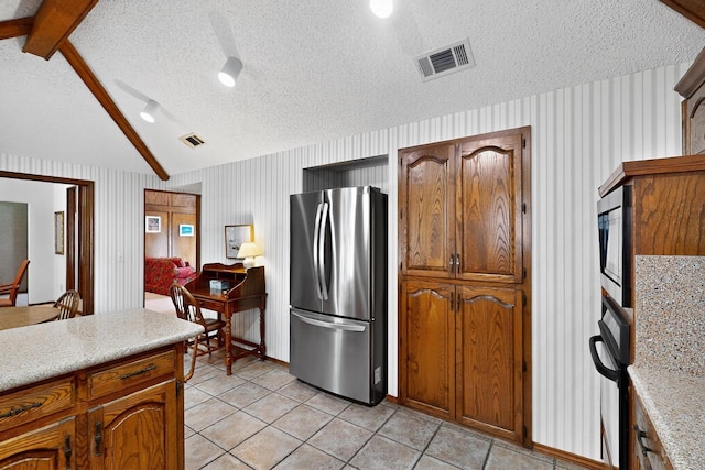 2521 La Vida Pl, Plano, TX 75023 - kitchen with stainless steel appliances, light countertops, light tile patterned floors, a textured ceiling, and brown cabinetry