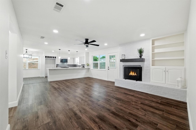 2428 Meadow Crk, Bedford, TX 76021 - unfurnished living room with dark wood-type flooring, a fireplace, recessed lighting, a ceiling fan, and built in shelves