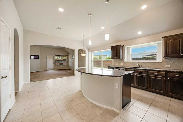 2133 Blakely Ct, Fort Worth, TX 76134 - kitchen featuring arched walkways, a sink, dark stone counters, a kitchen island, and decorative backsplash