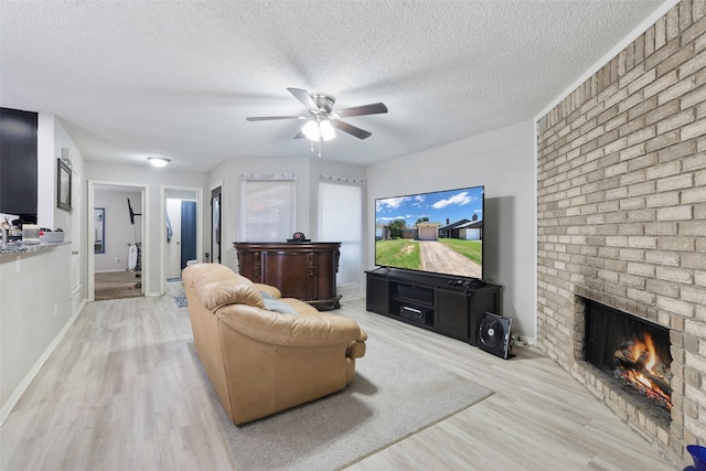 6624 S Creek Dr, Fort Worth, TX 76133 - living area with light wood-style flooring, a brick fireplace, a ceiling fan, and a textured ceiling