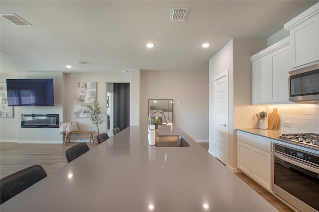 4007 Buckeye Bnd, Melissa, TX 75454 - kitchen featuring stainless steel appliances, a sink, wood finished floors, white cabinets, and recessed lighting