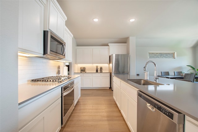 4007 Buckeye Bnd, Melissa, TX 75454 - kitchen featuring stainless steel appliances, a sink, light wood-style floors, tasteful backsplash, and white cabinets