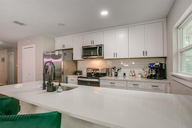 2110 Montana Trl, Grand Prairie, TX 76001 - kitchen with appliances with stainless steel finishes, a sink, tasteful backsplash, white cabinetry, and light countertops