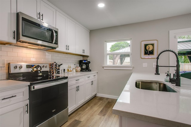 2110 Montana Trl, Grand Prairie, TX 76001 - kitchen featuring appliances with stainless steel finishes, a sink, tasteful backsplash, light wood finished floors, and white cabinetry