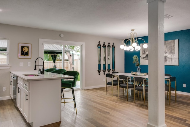 2110 Montana Trl, Grand Prairie, TX 76001 - kitchen with a sink, light wood-type flooring, white cabinetry, a breakfast bar, and light countertops