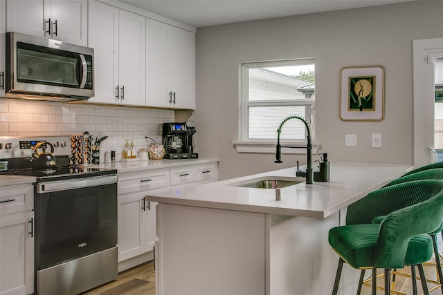 2110 Montana Trl, Grand Prairie, TX 76001 - kitchen featuring appliances with stainless steel finishes, a sink, a kitchen breakfast bar, decorative backsplash, and light countertops