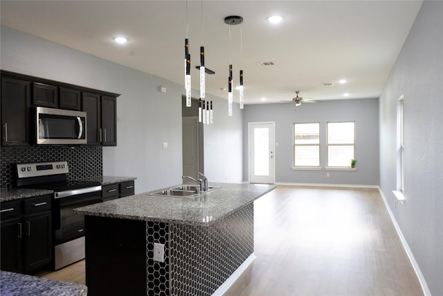 1610 Seadrift Dr, Forney, TX 75126 - kitchen featuring stainless steel appliances, light wood-style floors, ceiling fan, decorative backsplash, and a kitchen island with sink