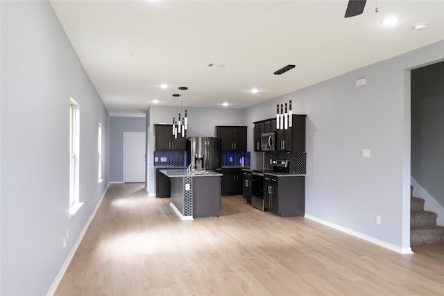 1610 Seadrift Dr, Forney, TX 75126 - kitchen with appliances with stainless steel finishes, tasteful backsplash, an island with sink, light wood finished floors, and pendant lighting